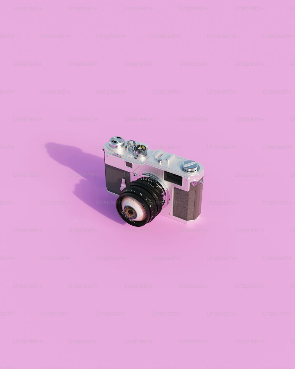 una fotocamera su sfondo rosa con un obiettivo
