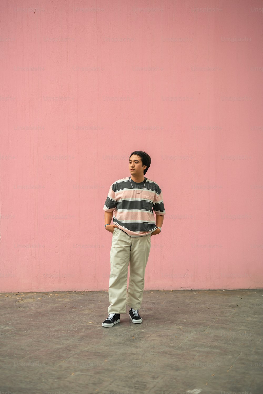 a man standing in front of a pink wall