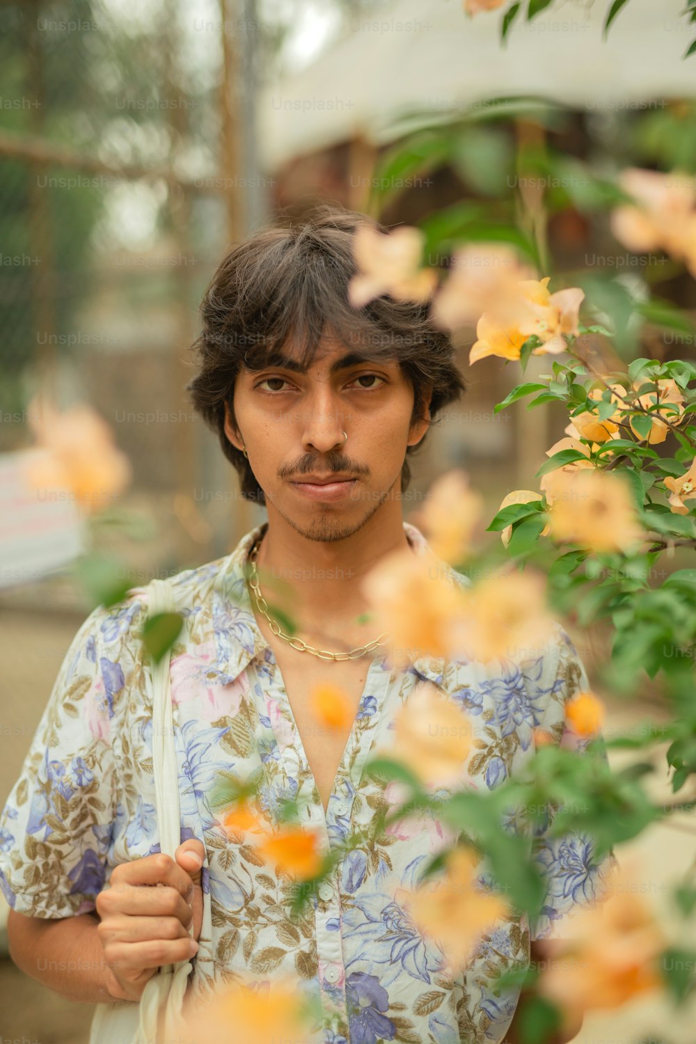a man with a moustache standing in front of flowers