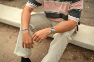 um homem sentado em um banco com um relógio inteligente no pulso