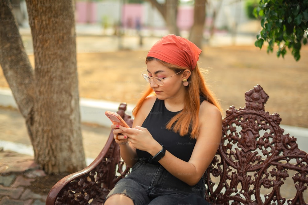 uma mulher sentada em um banco olhando para o celular