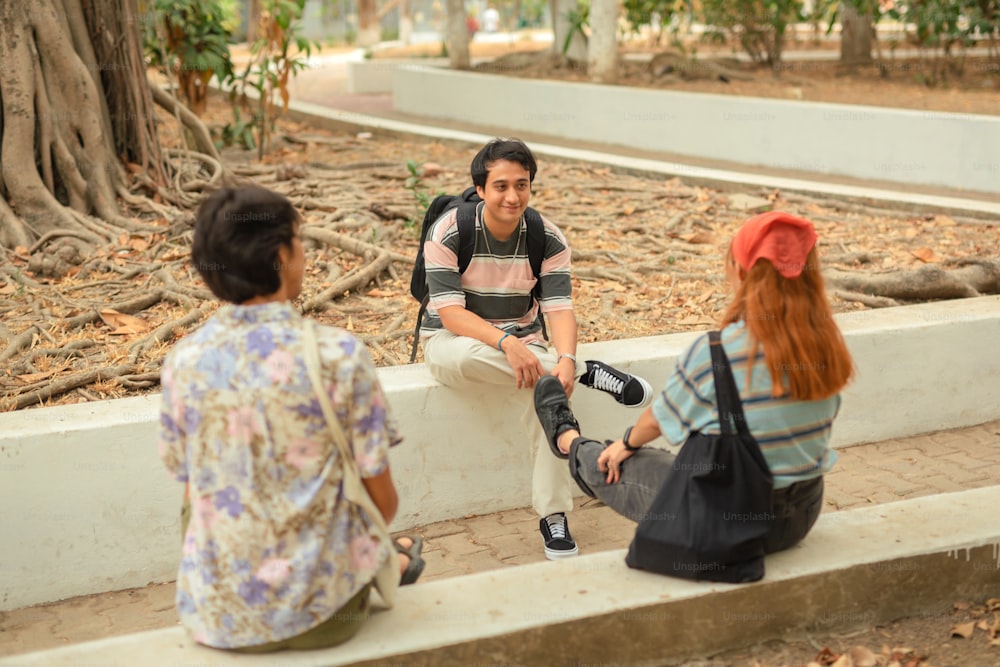 a man sitting on a ledge talking to two women