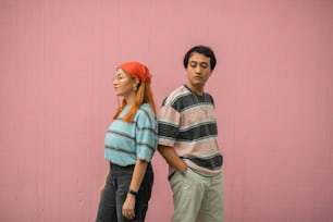 Un homme et une femme debout à côté d’un mur rose