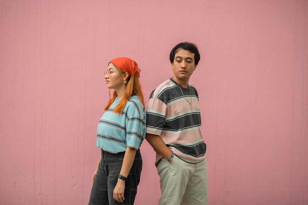 a man and a woman standing next to a pink wall
