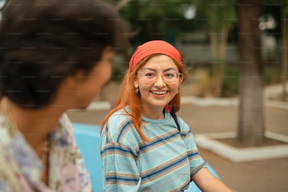 a woman with red hair and glasses talking to another woman