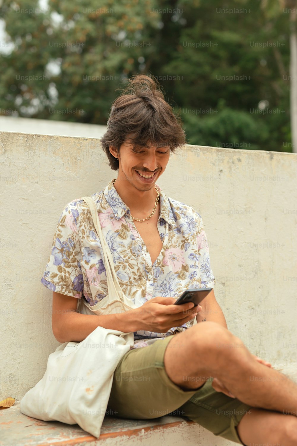Un uomo seduto su una sporgenza che guarda il suo cellulare