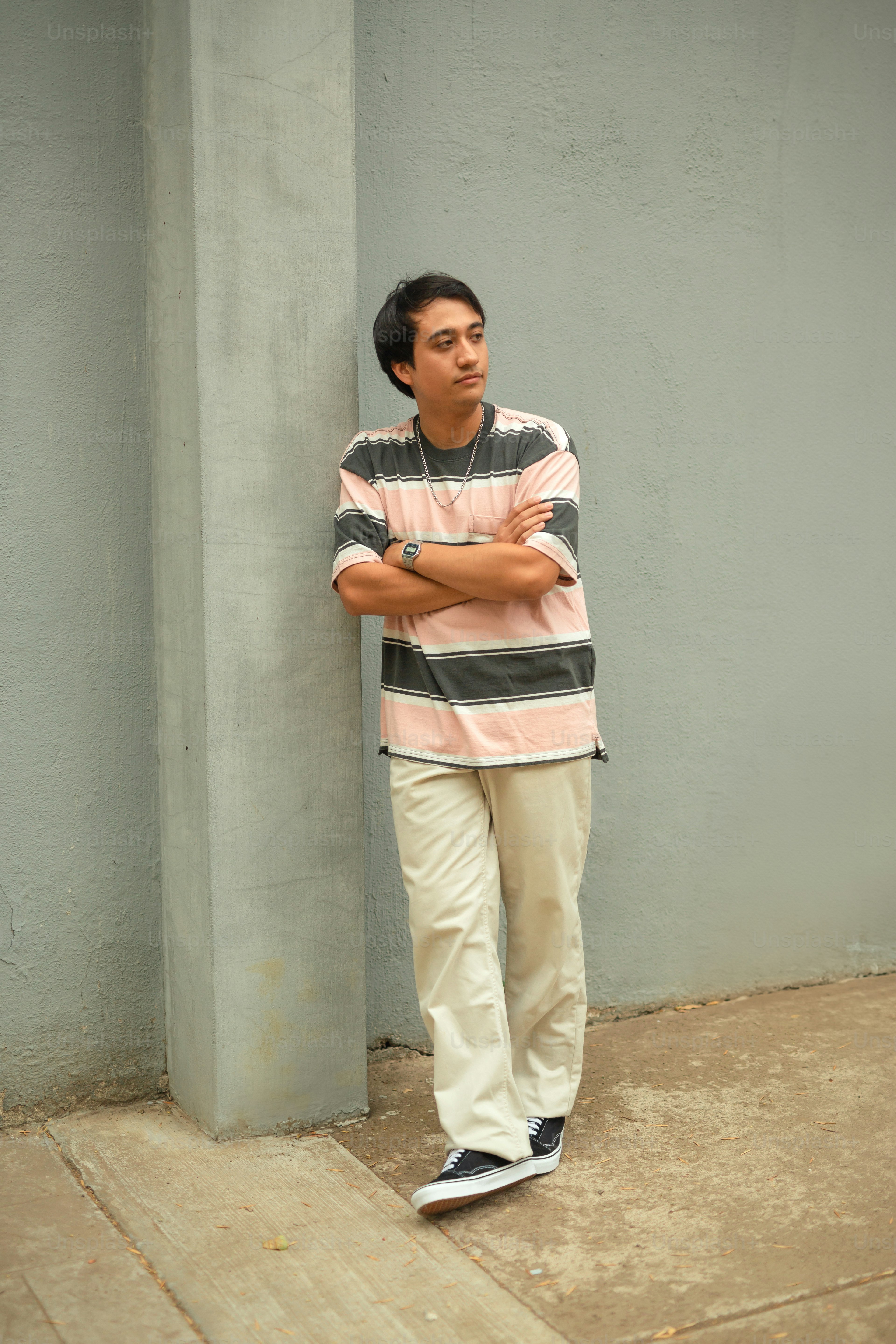 a man leaning against a wall with his arms crossed