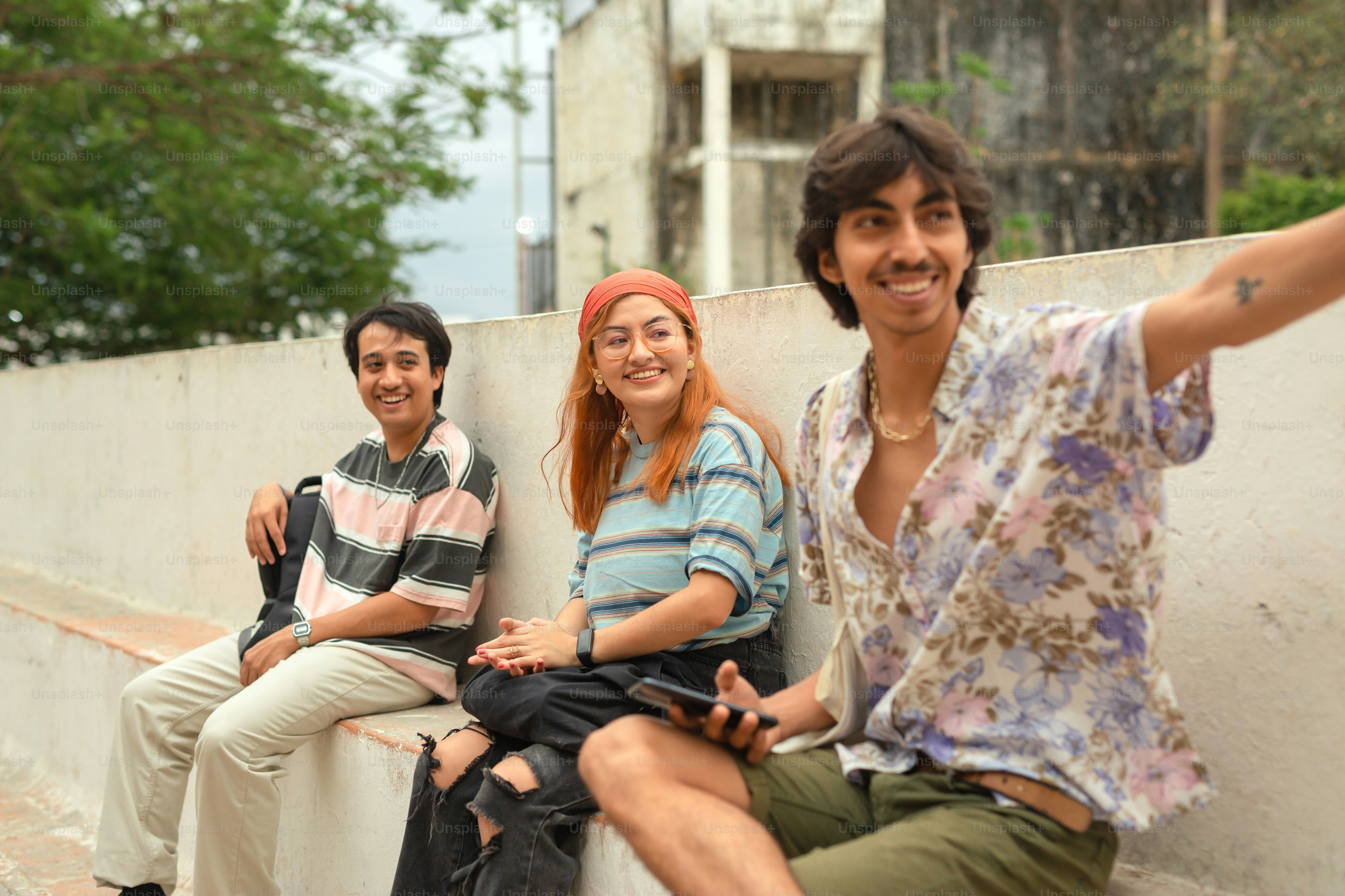 a group of people sitting on top of a cement wall