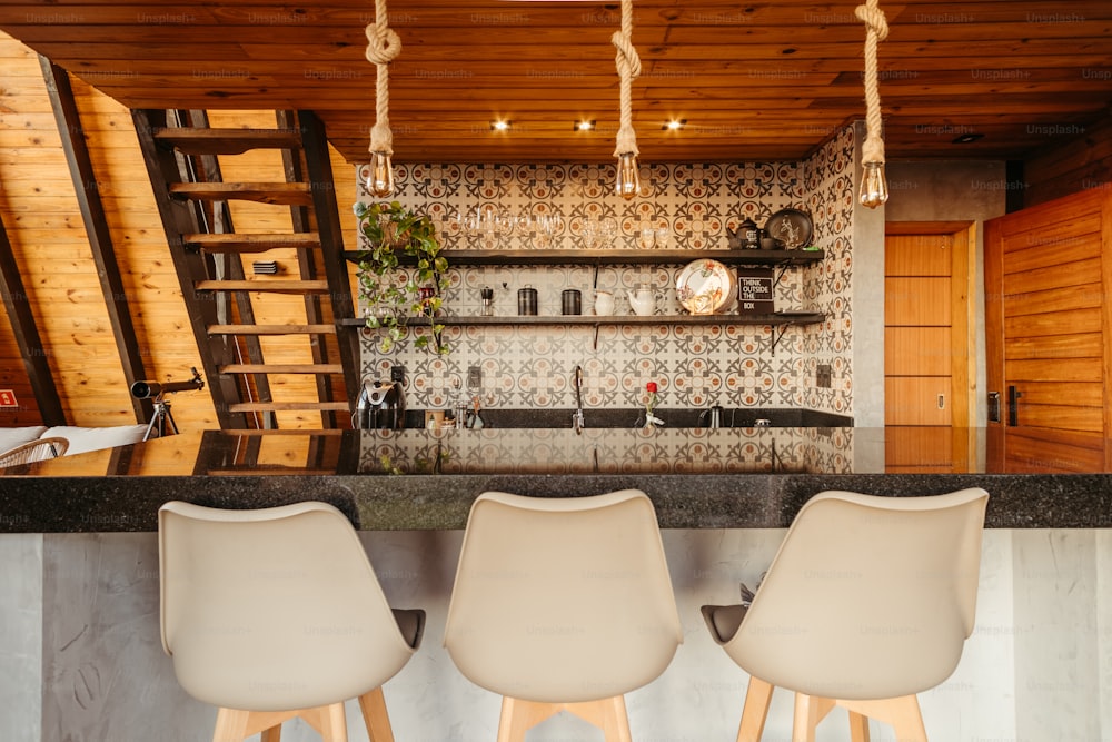 uma cozinha com um bar e três cadeiras