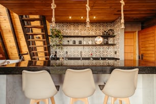 a kitchen with a bar and three chairs