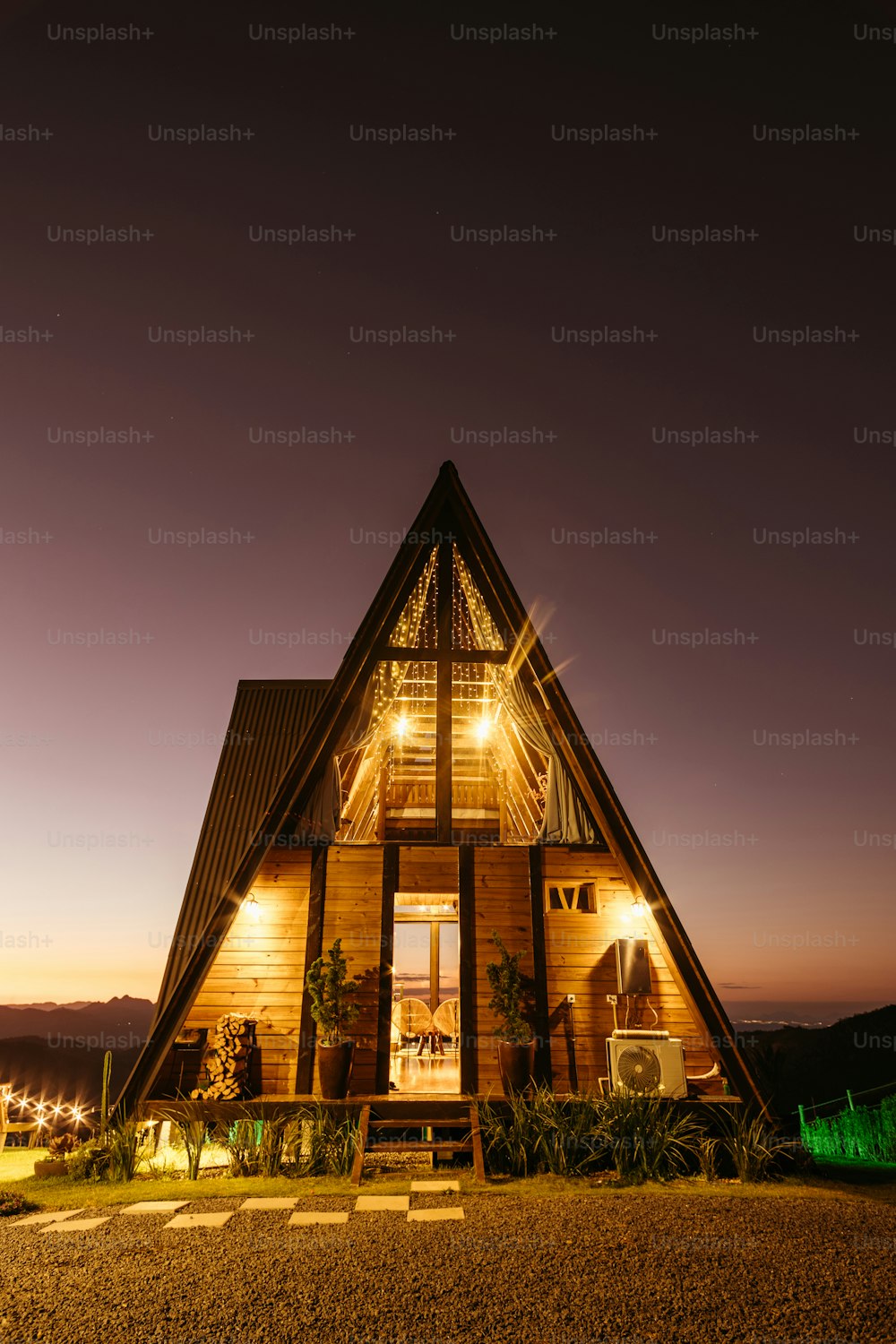 uma casa de madeira iluminada à noite em uma colina
