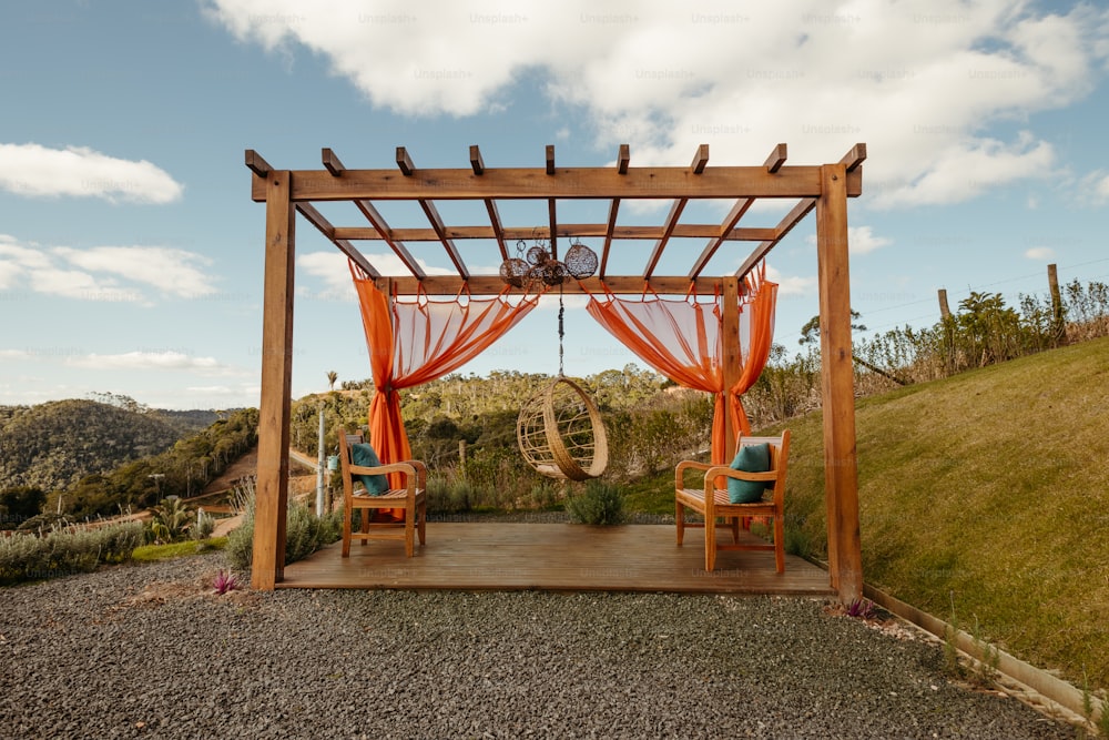 a couple of chairs sitting under a wooden gazebo