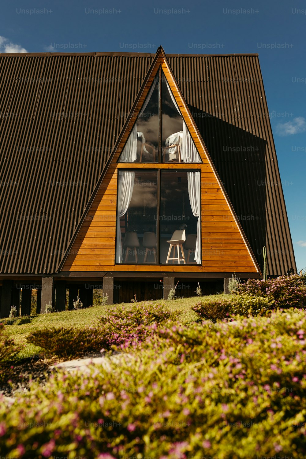 uma casa de madeira com uma grande janela ao lado dela