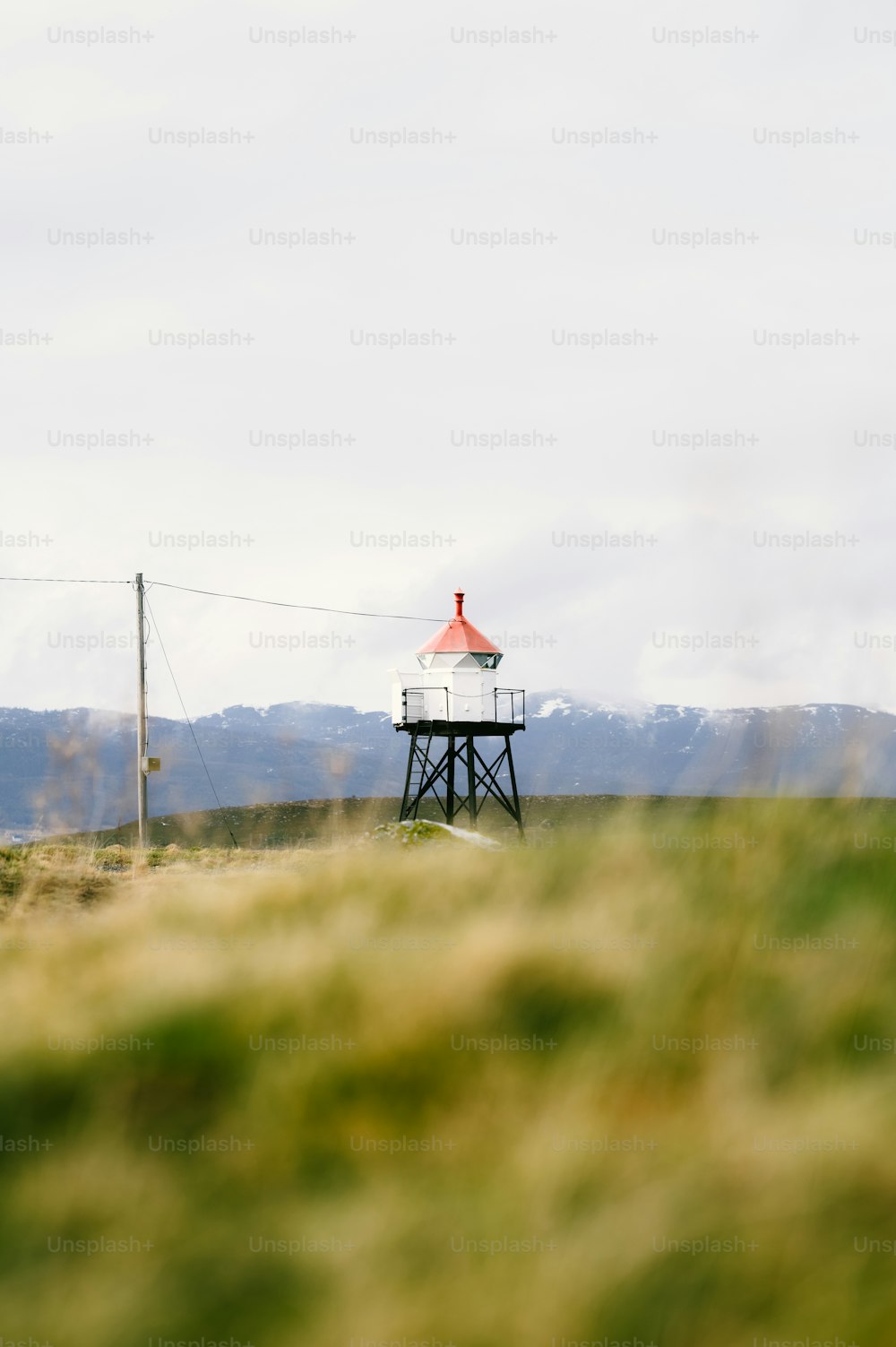 a small light house sitting on top of a lush green field