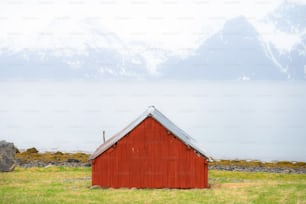 a red shed sitting on top of a lush green field