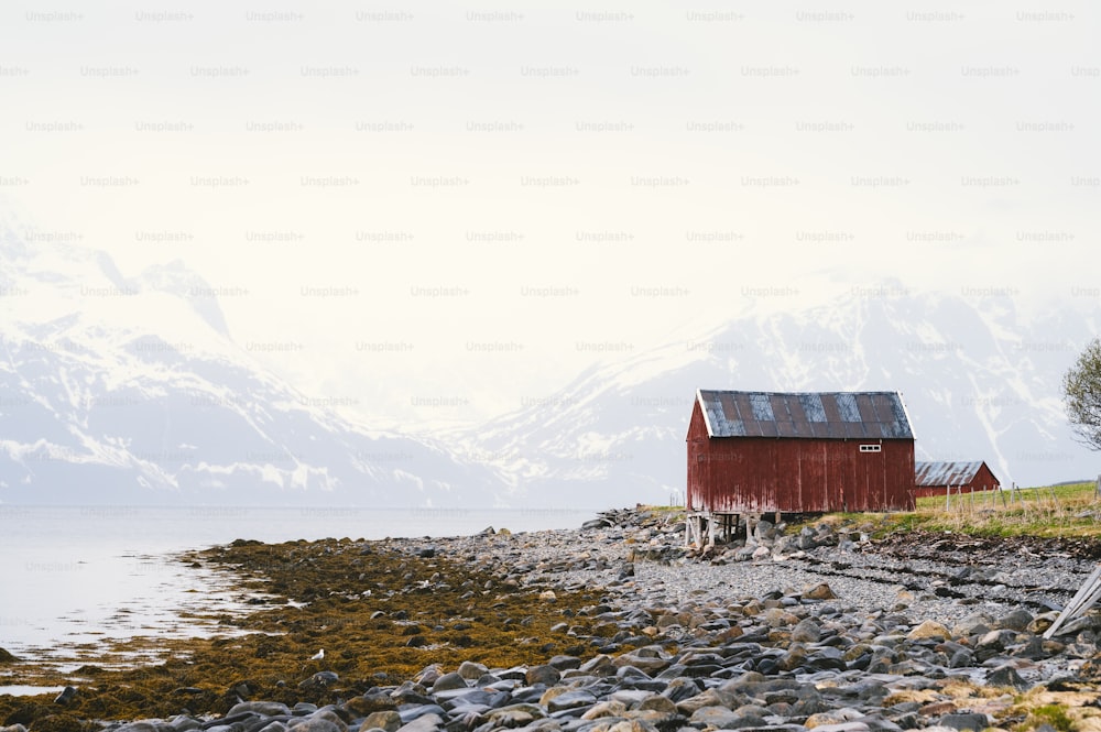 a red building sitting on top of a rocky beach