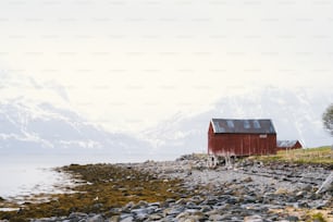 a red building sitting on top of a rocky beach