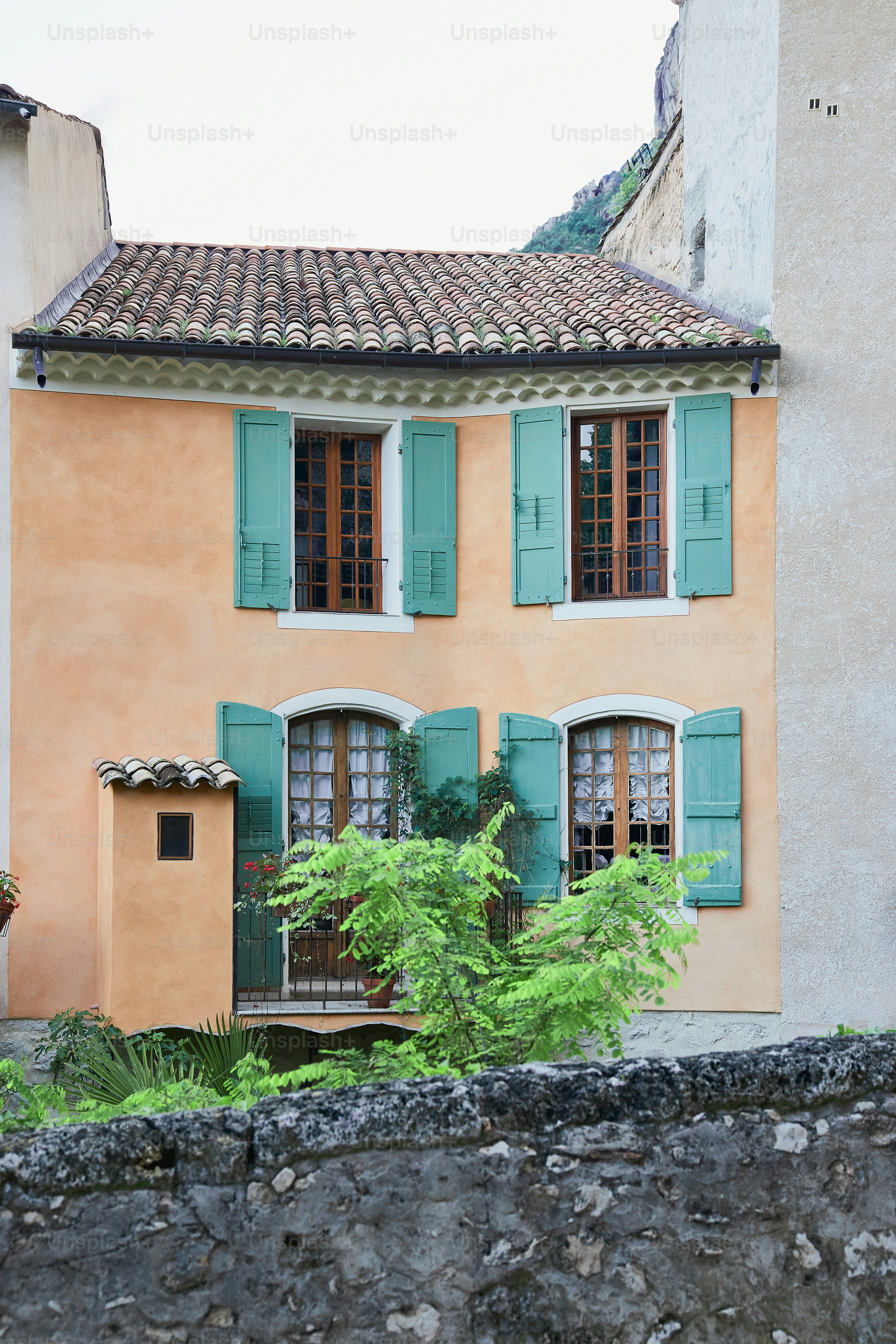 a house with green shutters and a stone wall