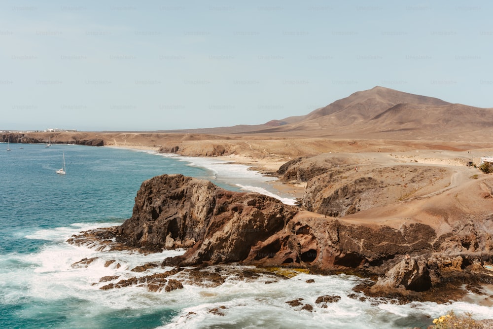 a view of a rocky coastline with a sailboat in the water