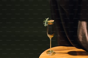 a glass of champagne with a sprig of rosemary on top