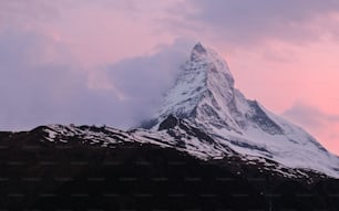 a snow covered mountain with a pink sky in the background