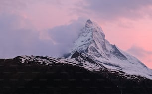 Una montagna innevata con un cielo rosa sullo sfondo