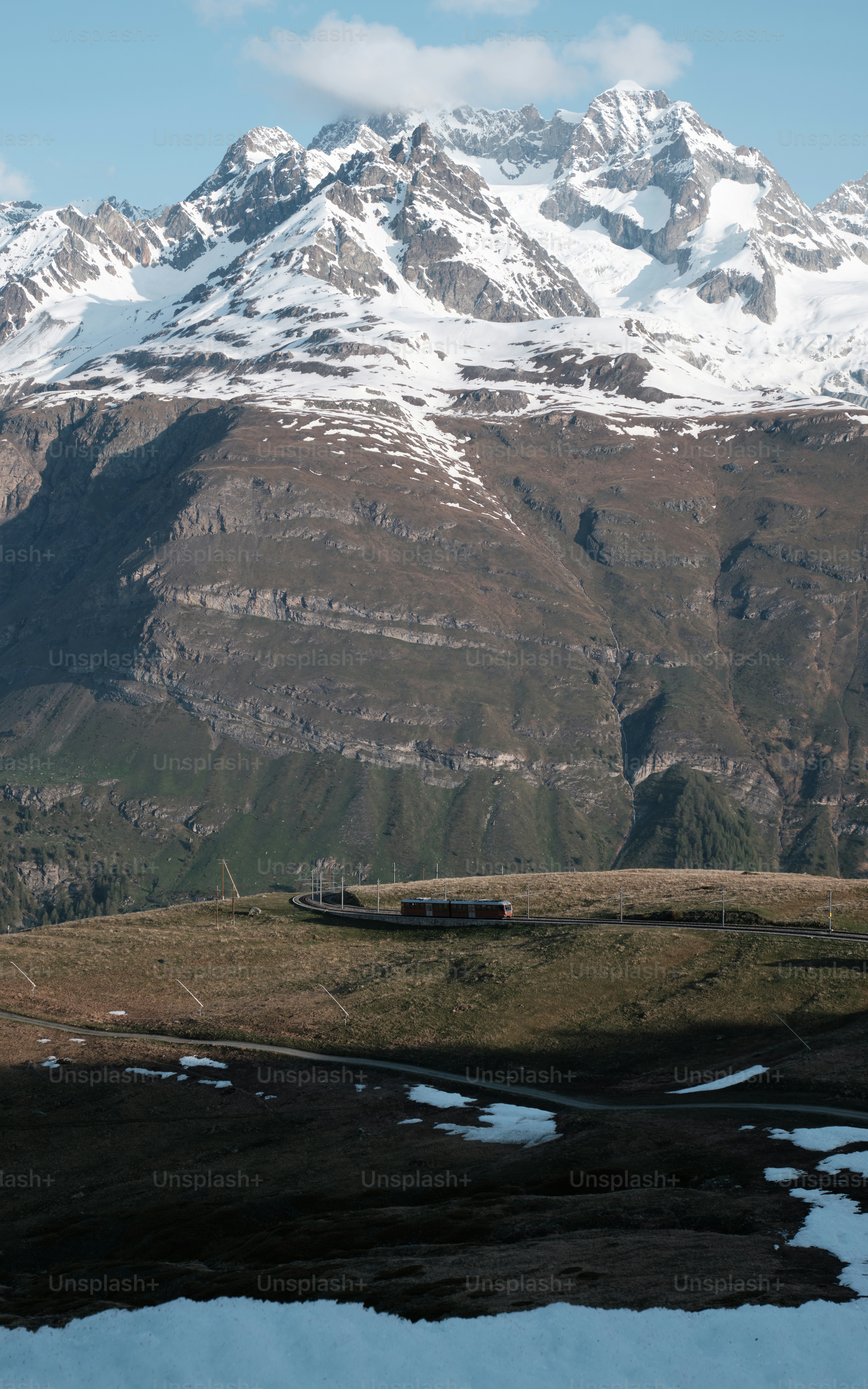 a snow covered mountain range with a train on the tracks