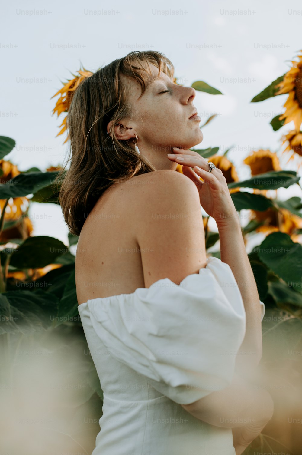 a woman in a white dress standing in a field of sunflowers