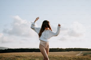 Una mujer con una camisa blanca y pantalones cortos de color canela corriendo por un campo