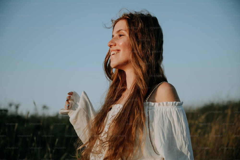 a woman standing in a field with her hair blowing in the wind