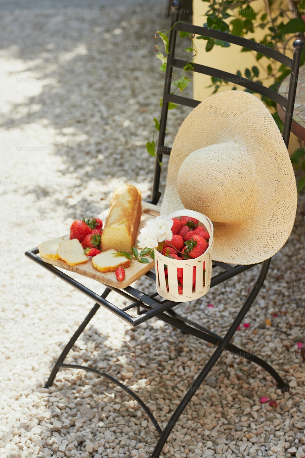 a straw hat sitting on top of a chair next to a plate of strawberries
