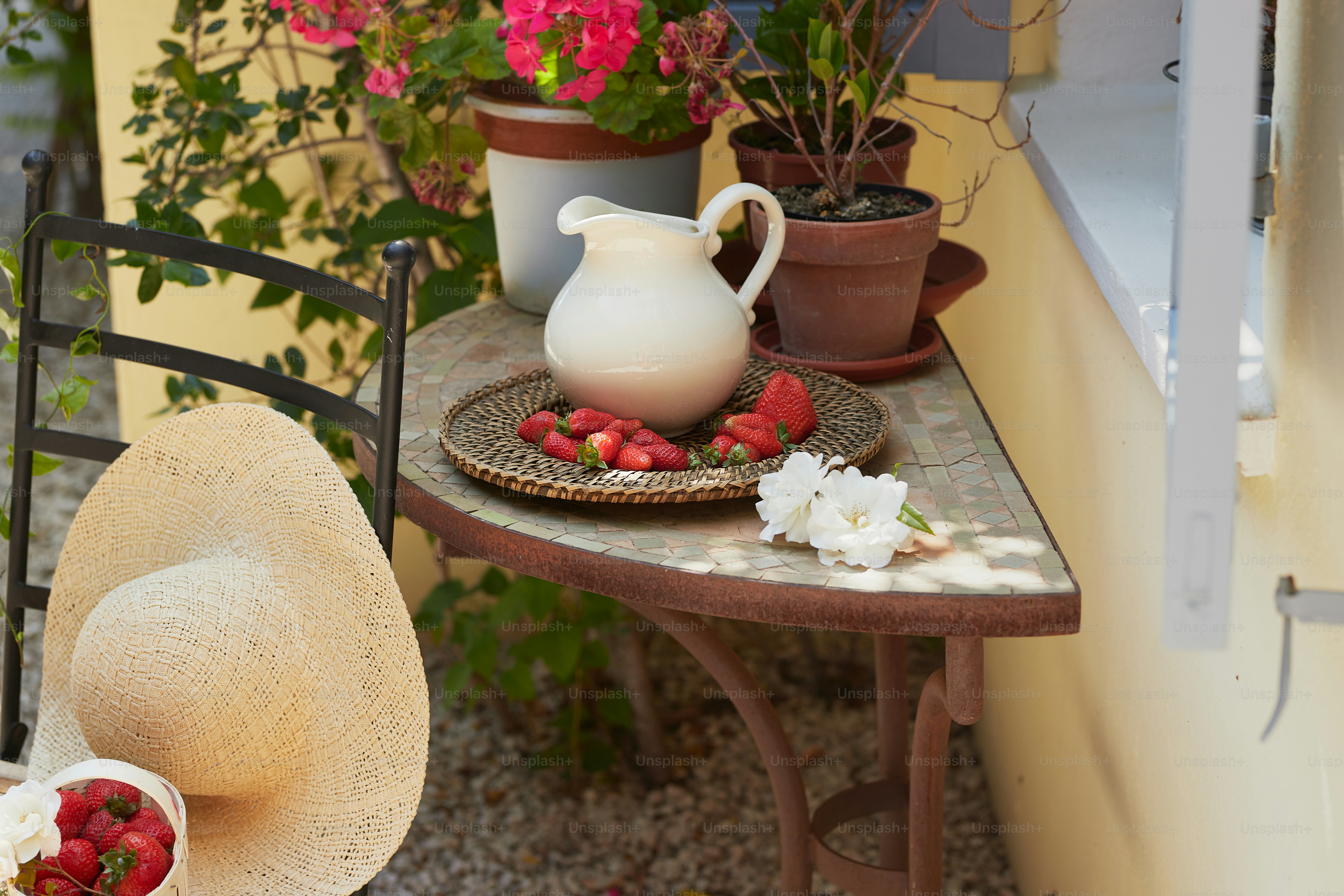 a table topped with a white pitcher of water and a plate of strawberries