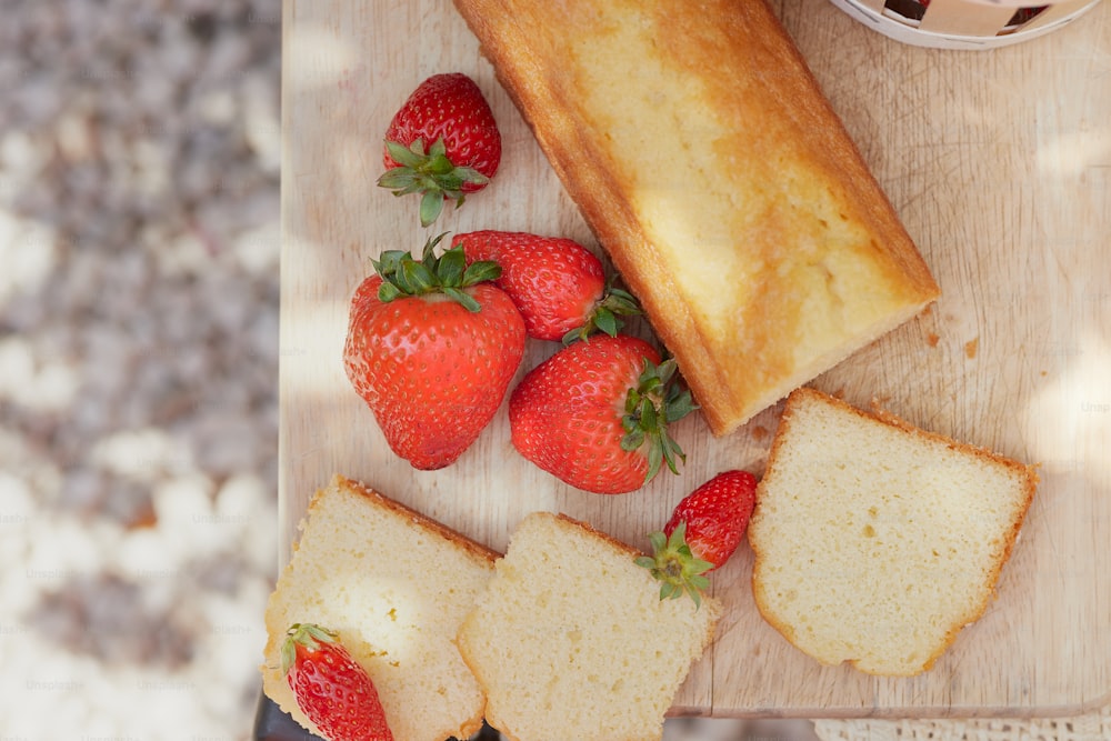 a cutting board topped with sliced bread and strawberries