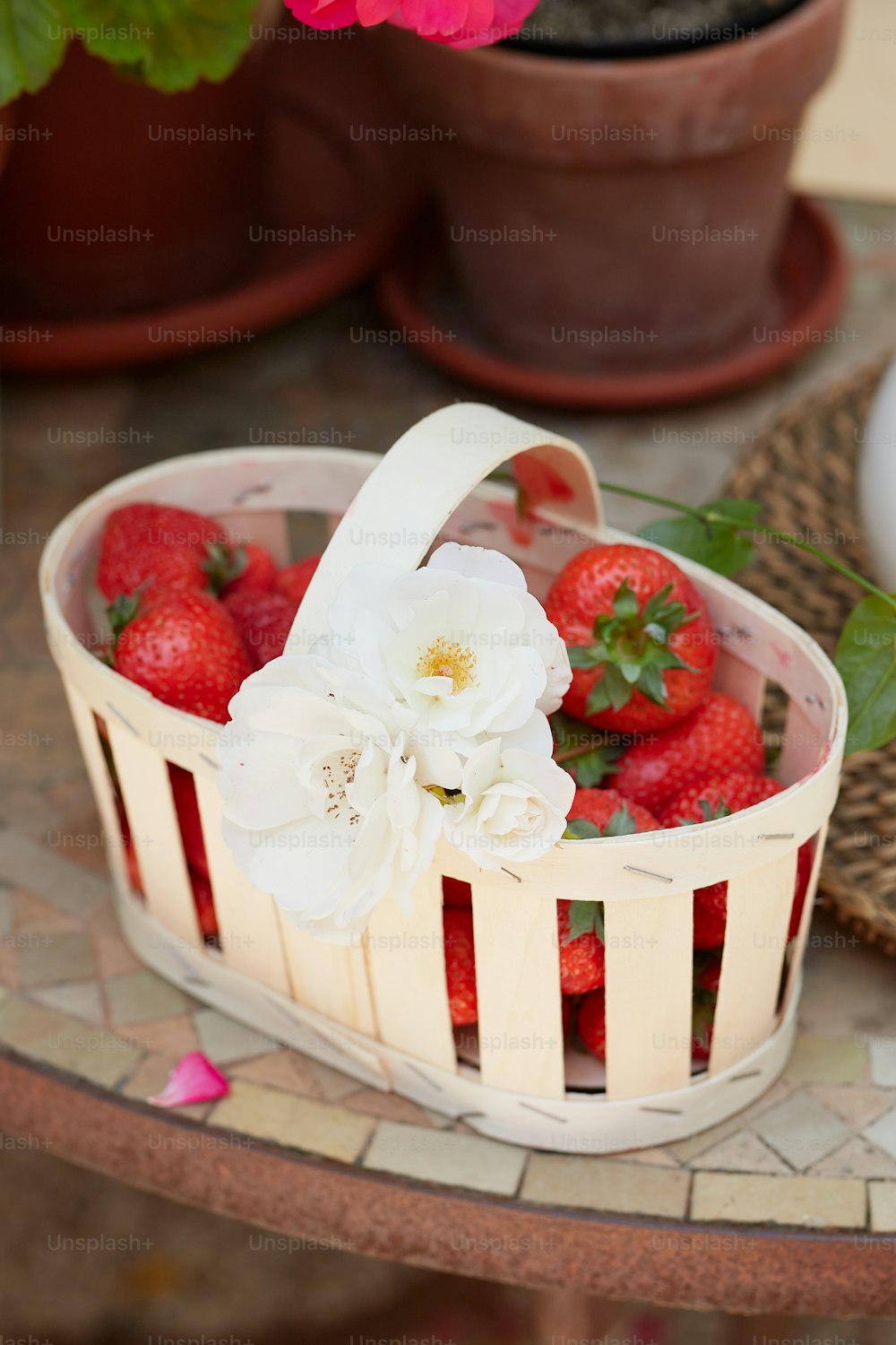 ein Korb mit Erdbeeren und Blumen auf einem Tisch