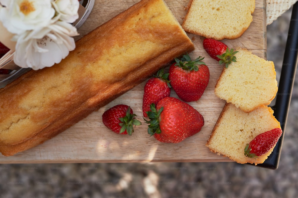 a wooden cutting board topped with sliced bread and strawberries