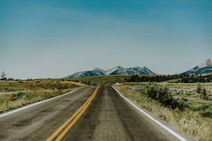 an empty road with mountains in the background