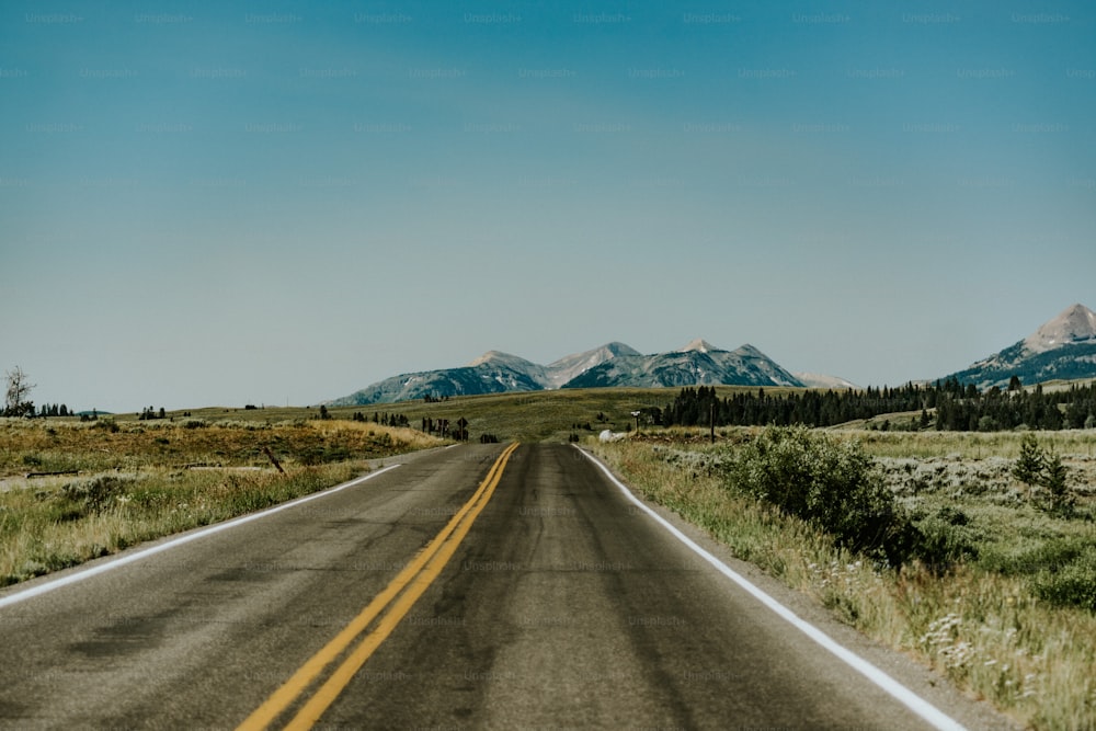 an empty road with mountains in the background