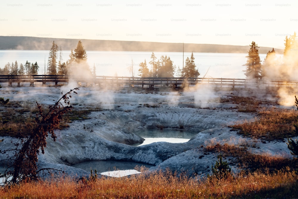 steam rises from the ground near a body of water