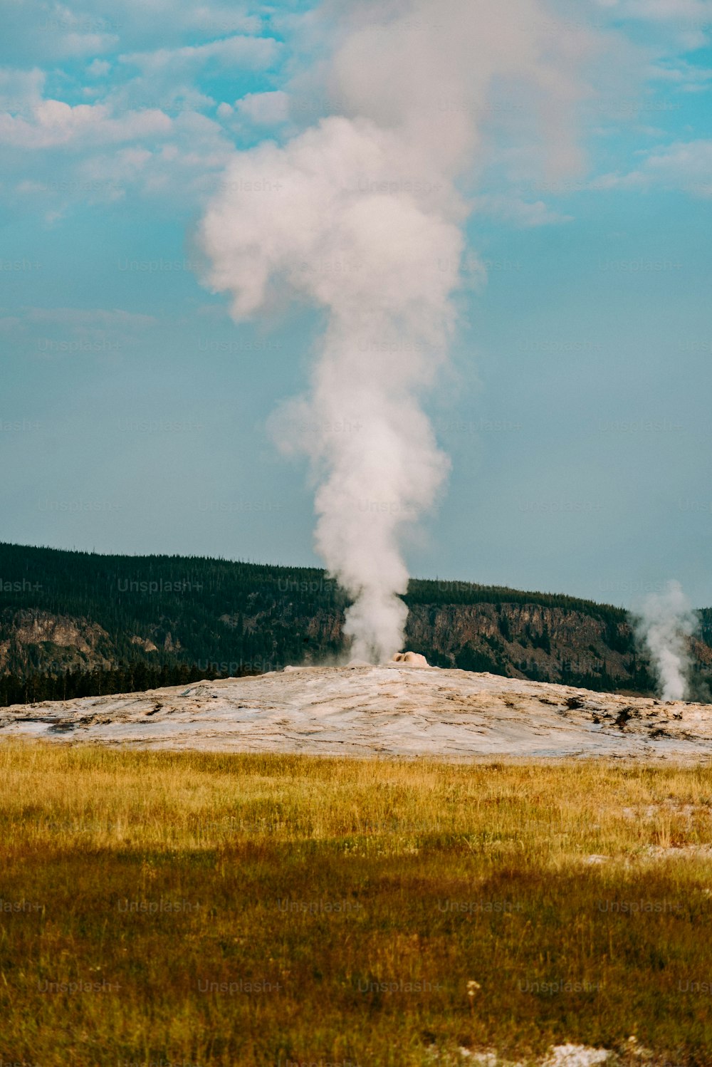 a geyser emits steam as it rises into the sky