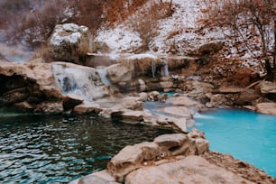 uma piscina de água cercada por pedras e uma cachoeira