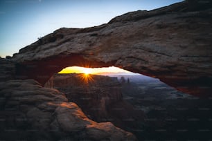 the sun is setting over a rocky cliff