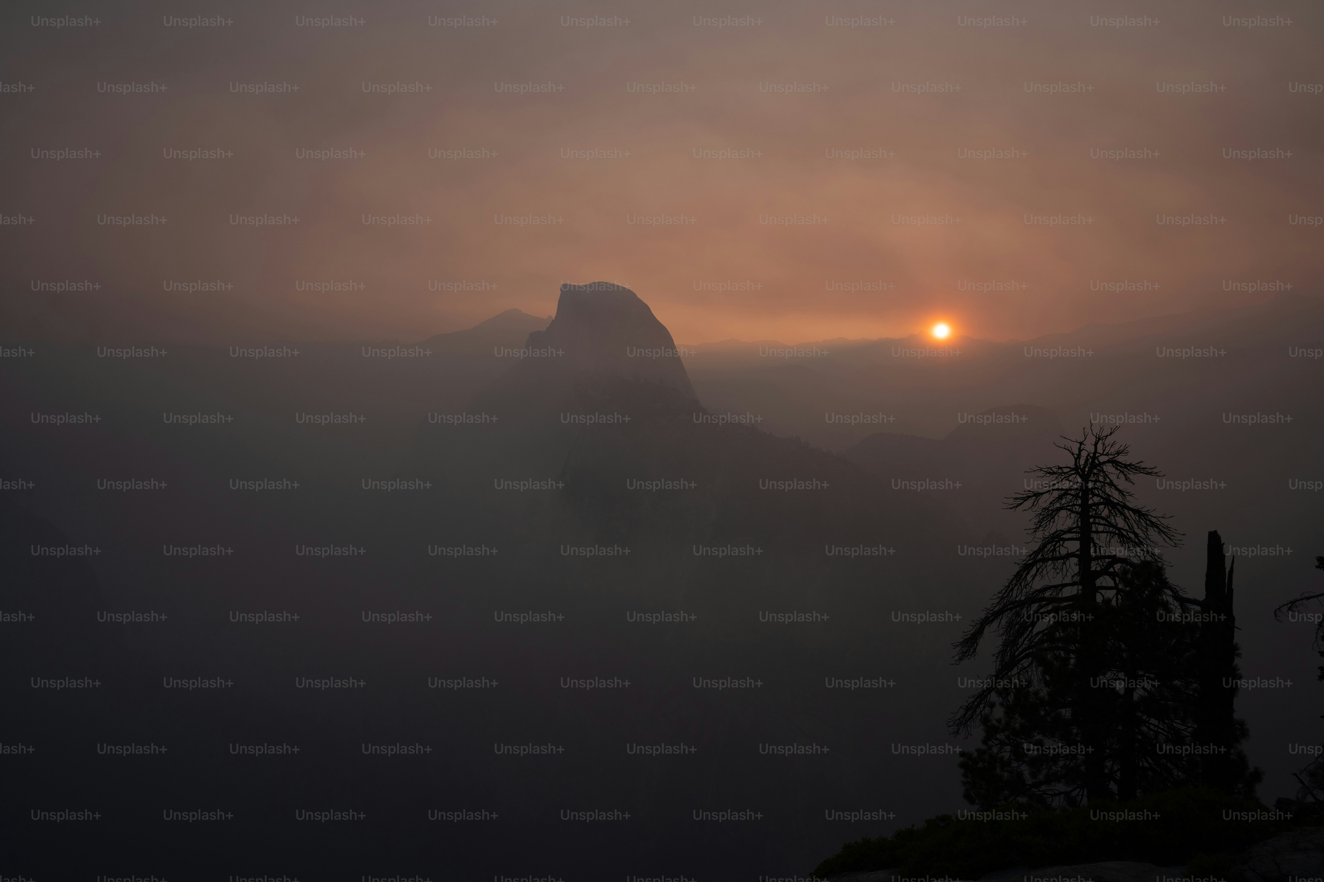 Le soleil se couche sur les montagnes dans le brouillard