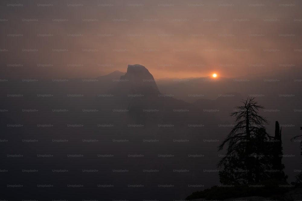 太陽は霧の中で山の上に沈んでいます