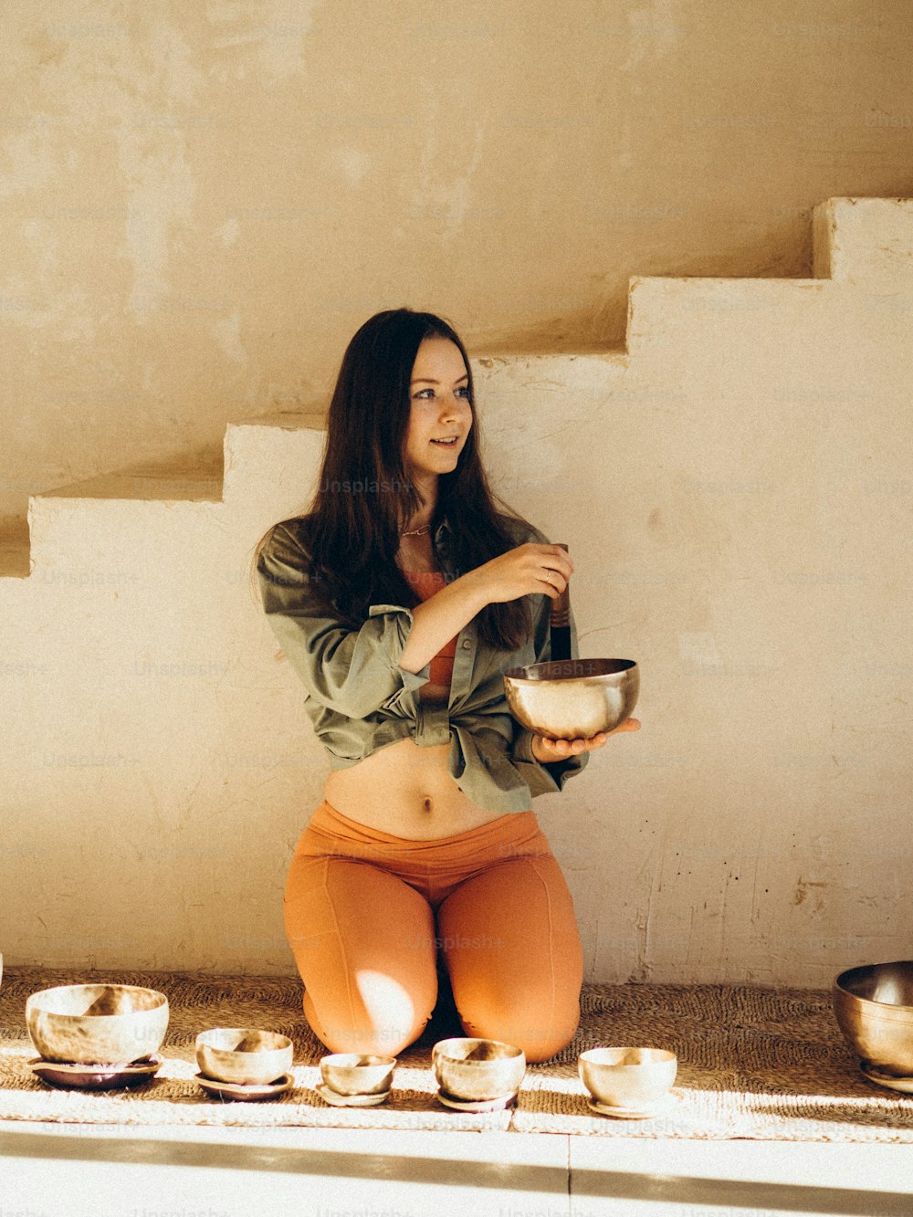 a woman sitting on the ground holding a bowl