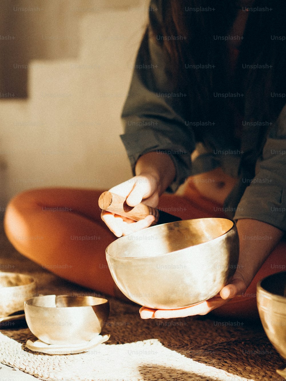 a woman sitting on the floor holding a silver bowl