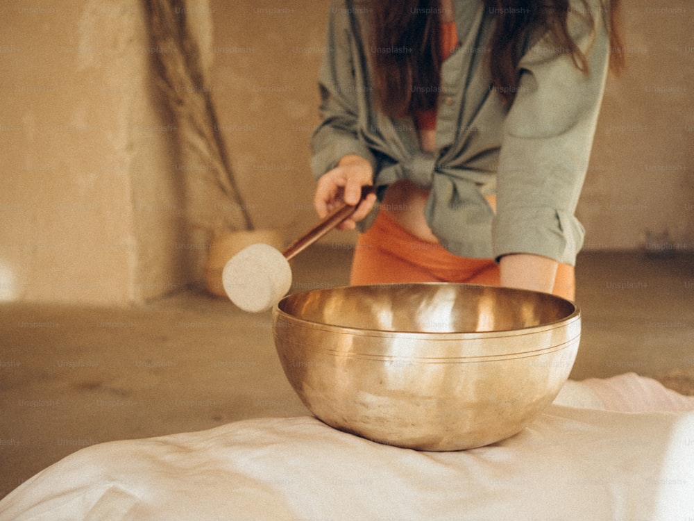 a woman mixing a large metal bowl with a wooden spoon