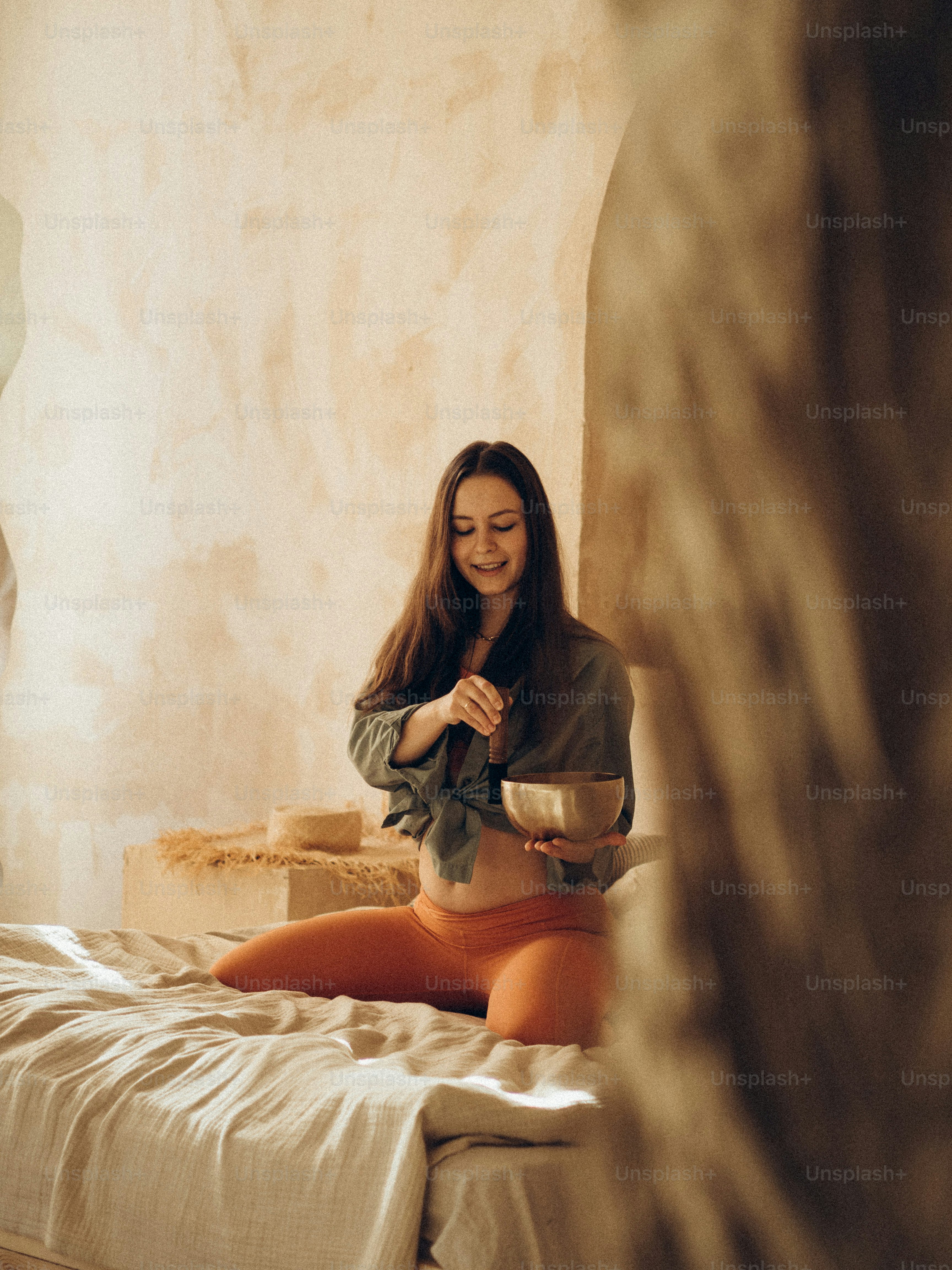 eine frau, die mit einer schüssel essen auf einem bett sitzt