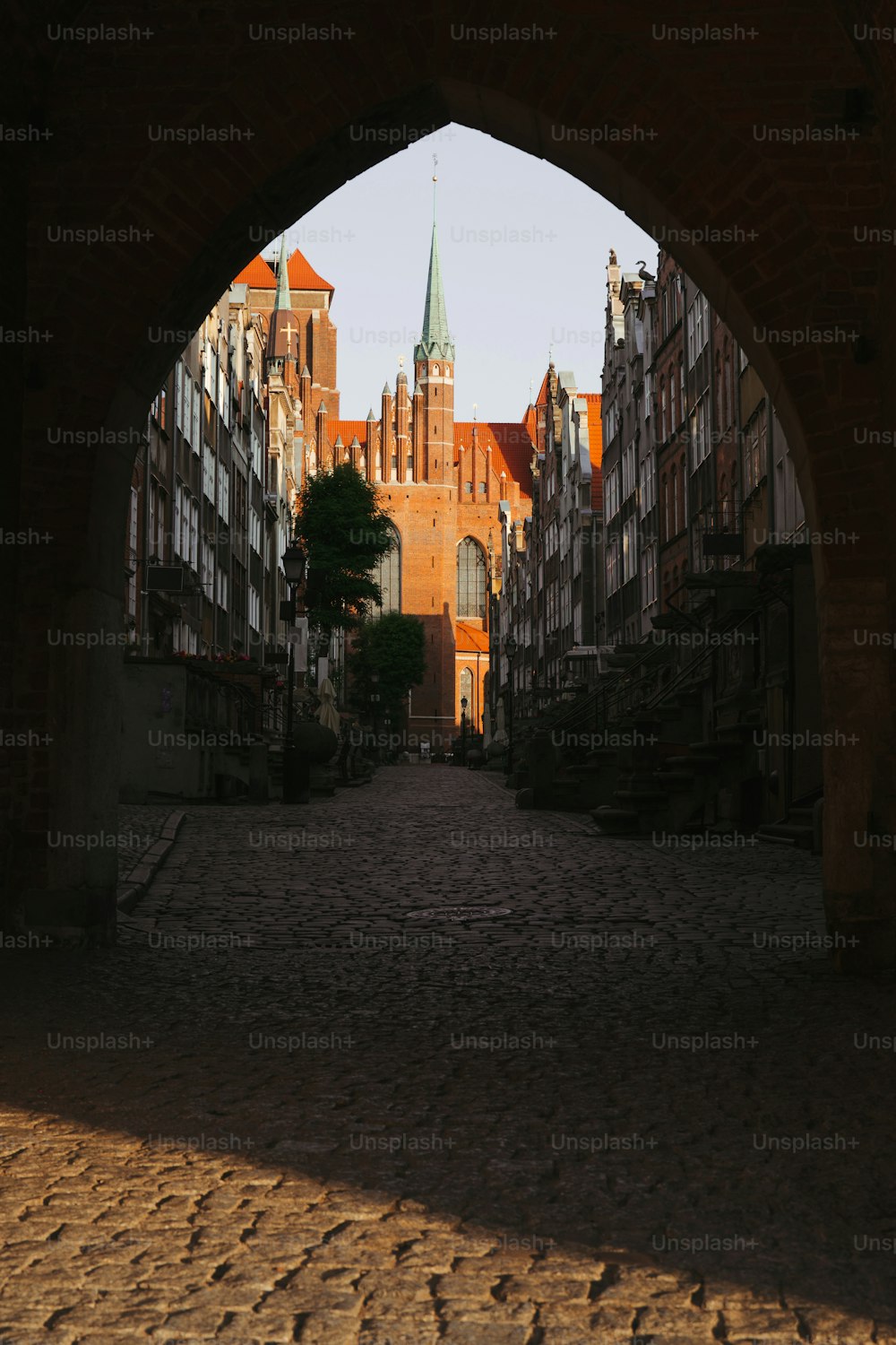 an arch in a brick building with a clock tower in the background