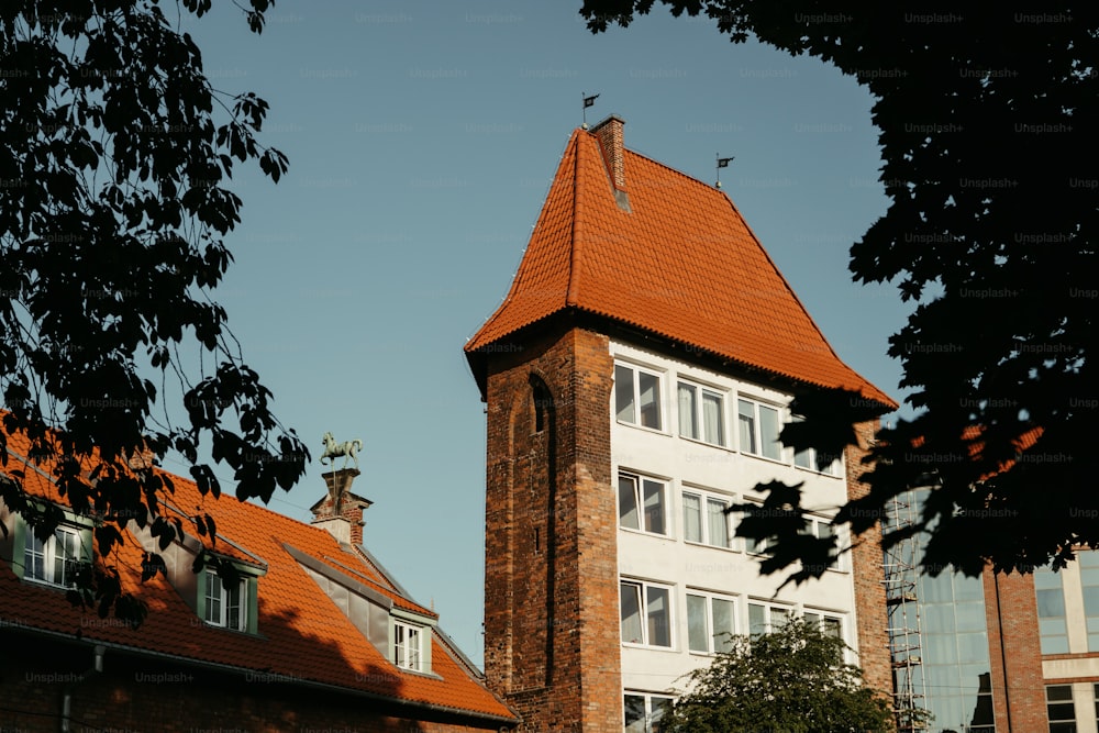 um edifício alto com um telhado vermelho e uma torre do relógio