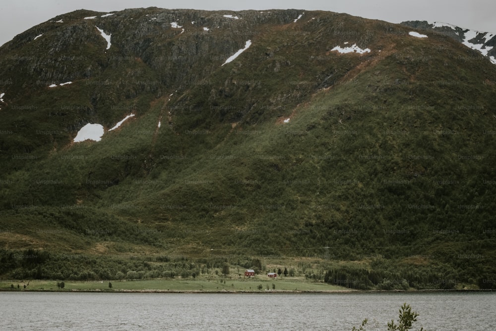 a mountain covered in snow next to a body of water